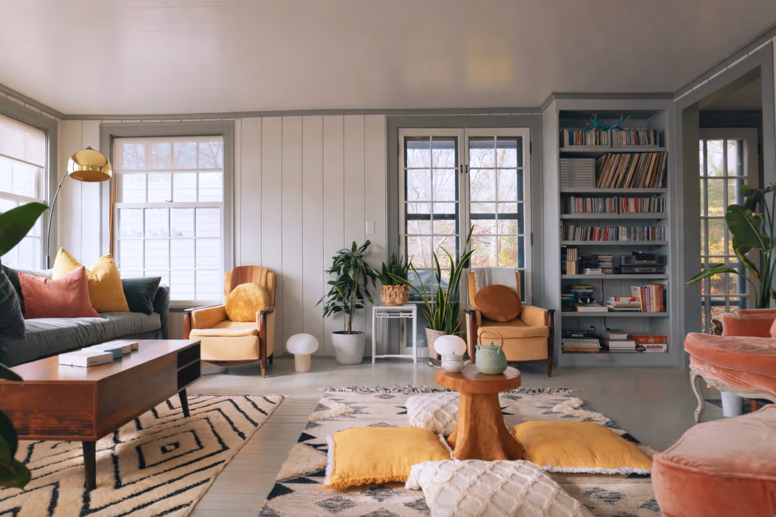 Cozy living room with yellow armchairs, a wooden coffee table, and a built-in bookshelf.