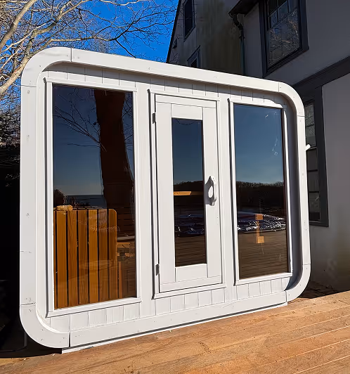 Modern white-framed large window reflecting outdoor scenery and a wooden deck.